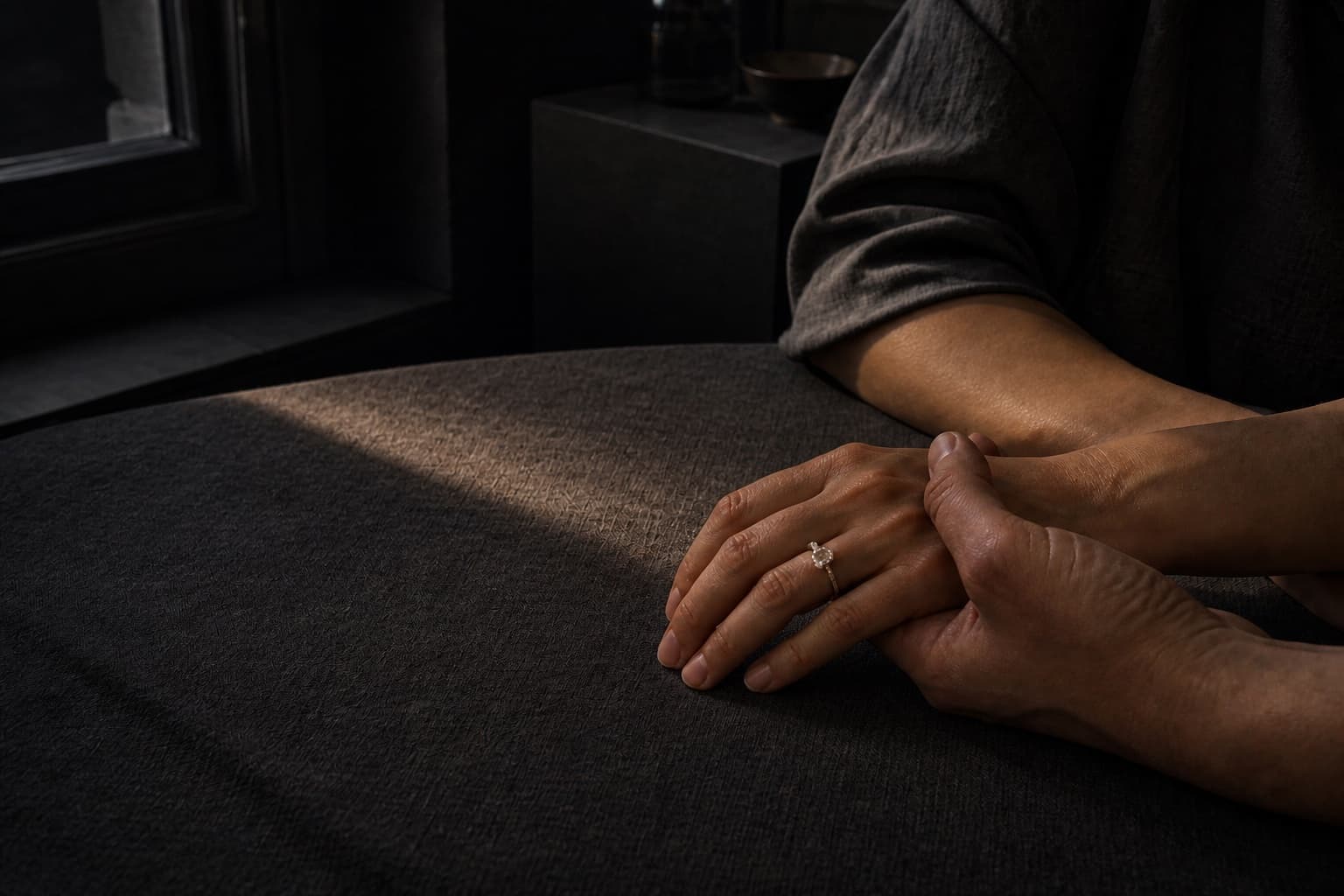 A diamond ring worn naturally while two people rest their hands together