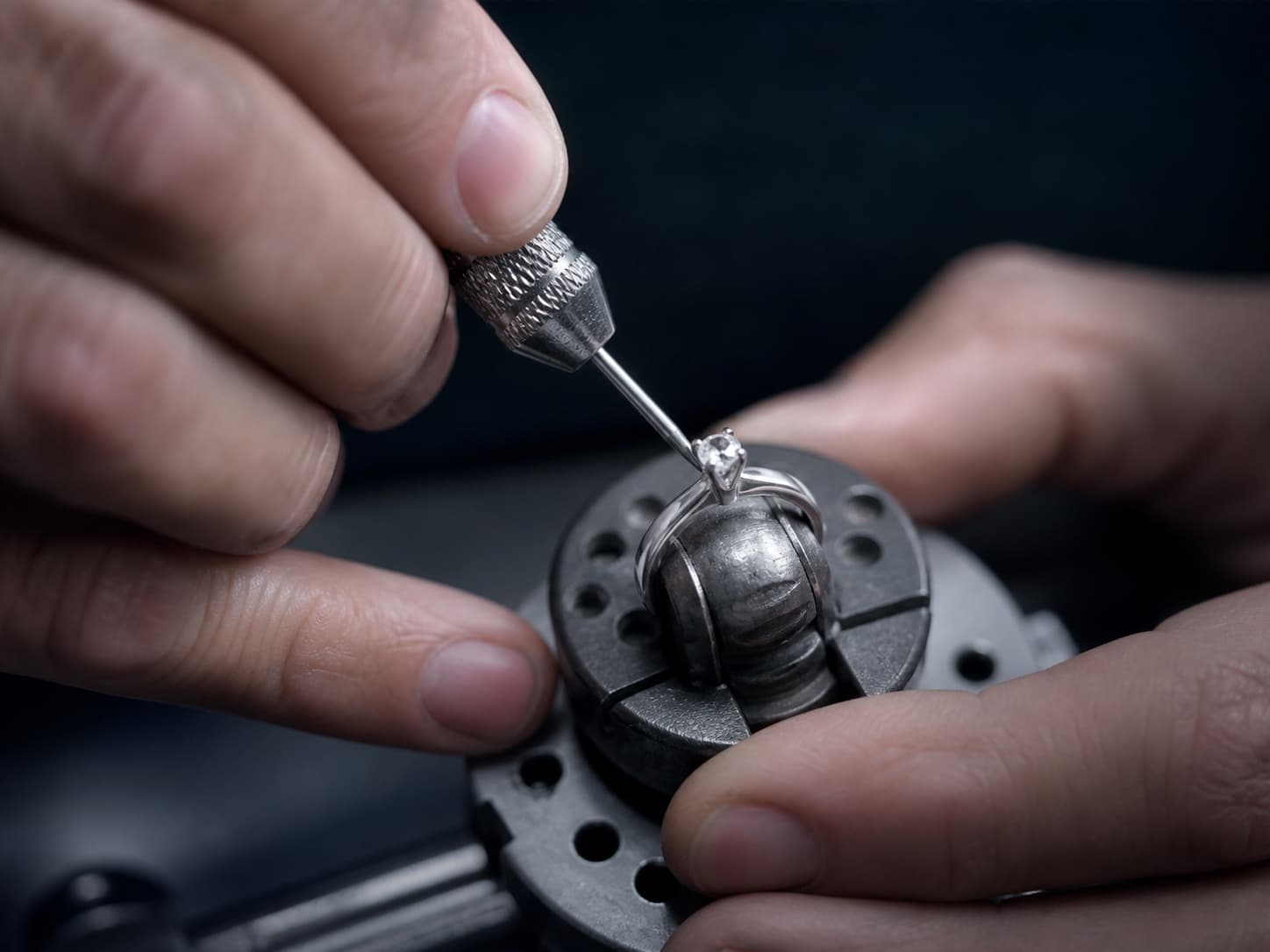 A jeweler setting a diamond into a platinum ring with a precision tool